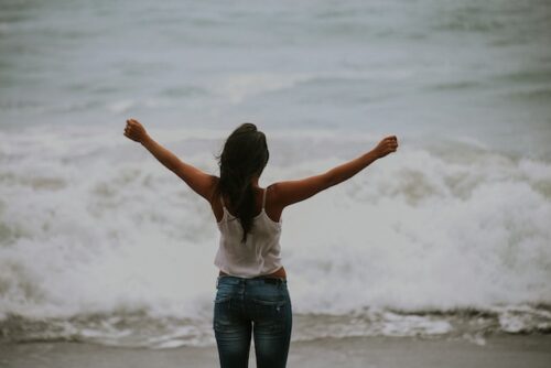 woman holding arms up at sea