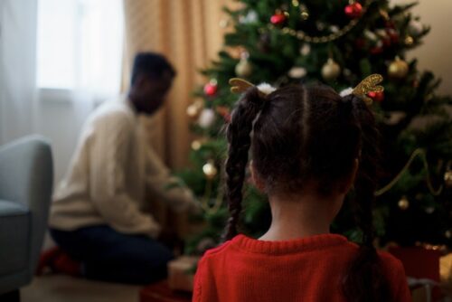 child standing in front of christmas tree